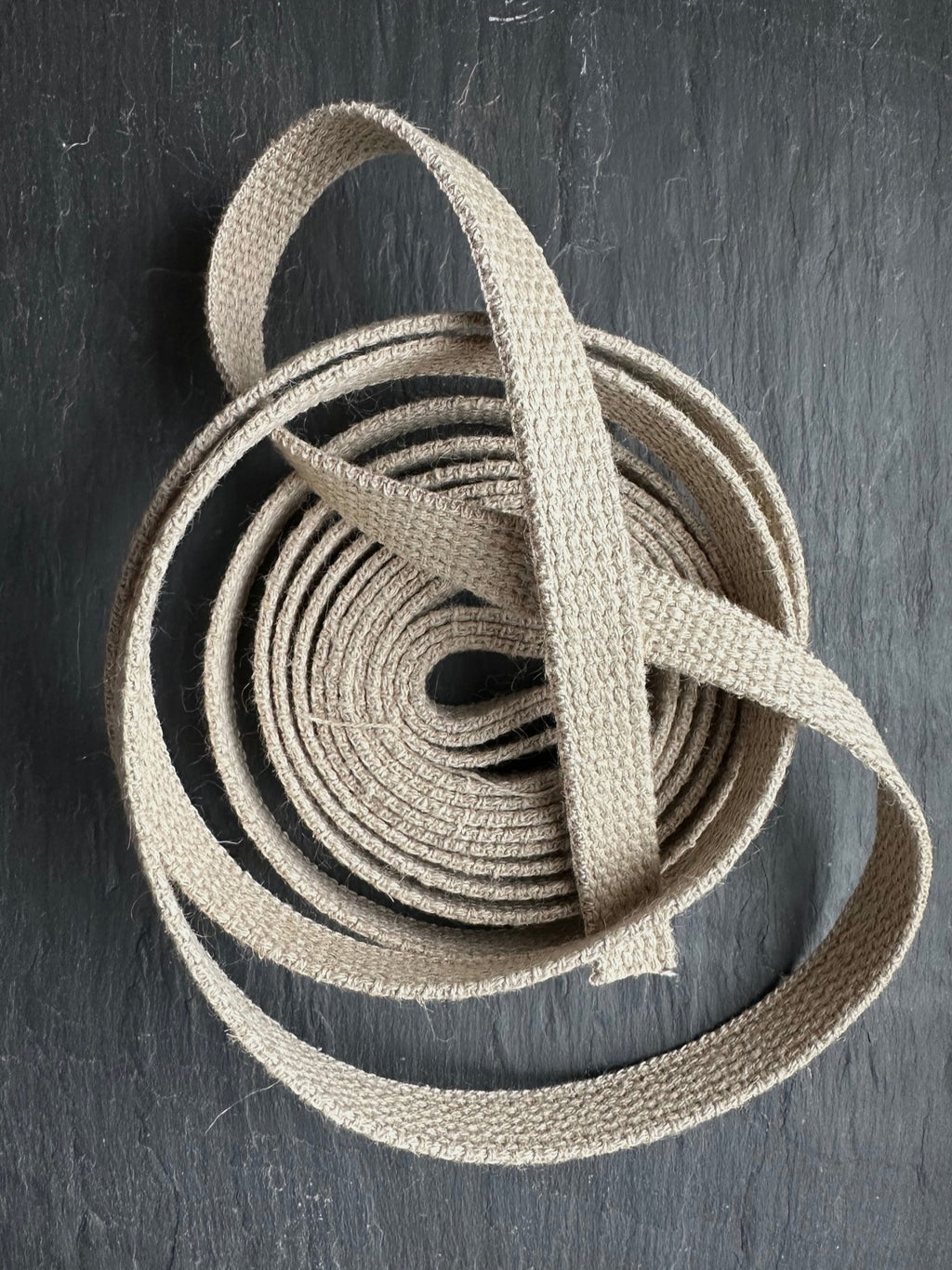 Coiled natural hemp webbing on a dark gray surface