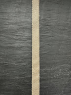 Narrow natural hemp webbing strip on a dark gray textured background