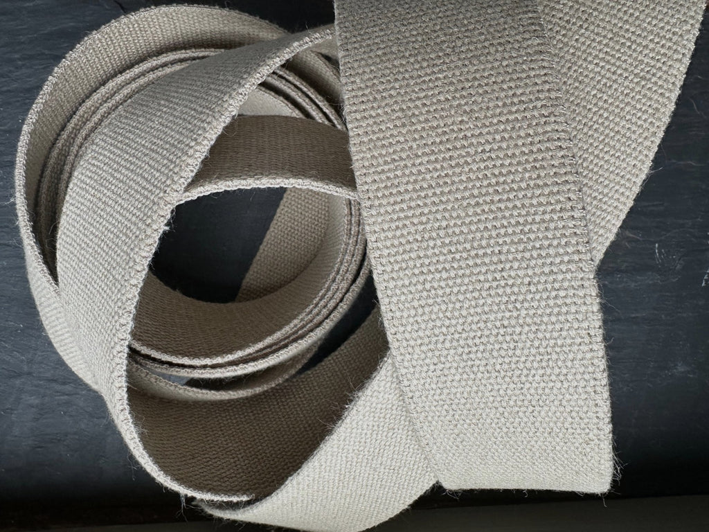 Close-up of a beige natural hemp webbing fabric strip on a dark background