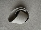 Close-up of a roll of grey natural hemp webbing fabric with a textured surface.