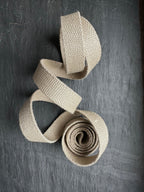 Beige woven hemp webbing piece on a dark textured surface