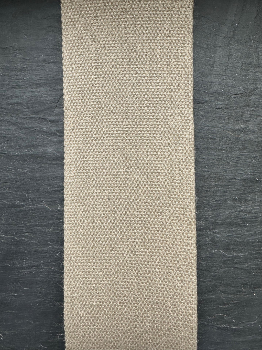 Beige woven hemp webbing strip on a dark textured surface