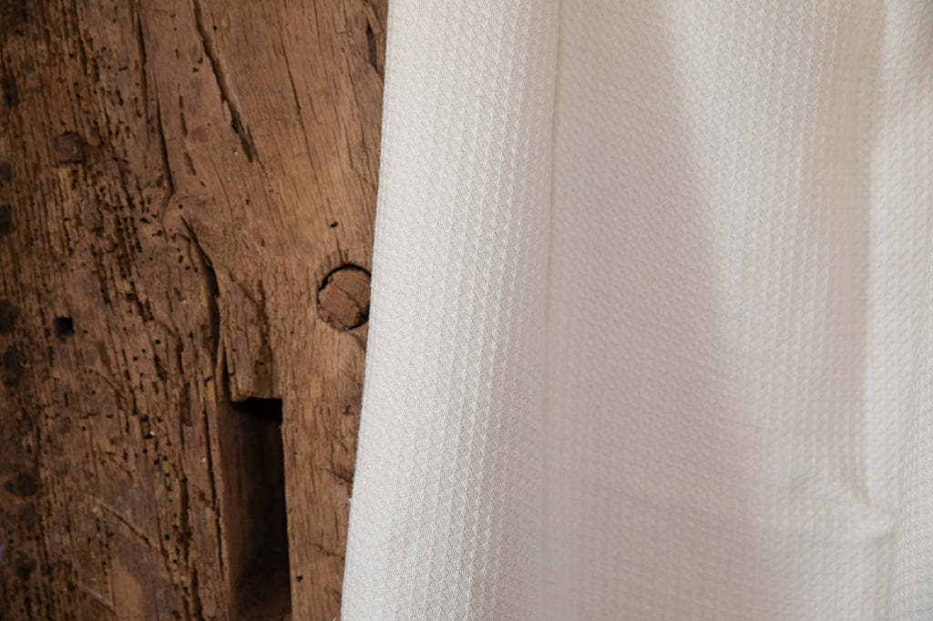 Close-up of textured Waffle white hemp fabric next to a wooden surface