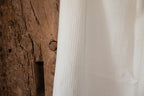 Close-up of textured Waffle white hemp fabric next to a wooden surface