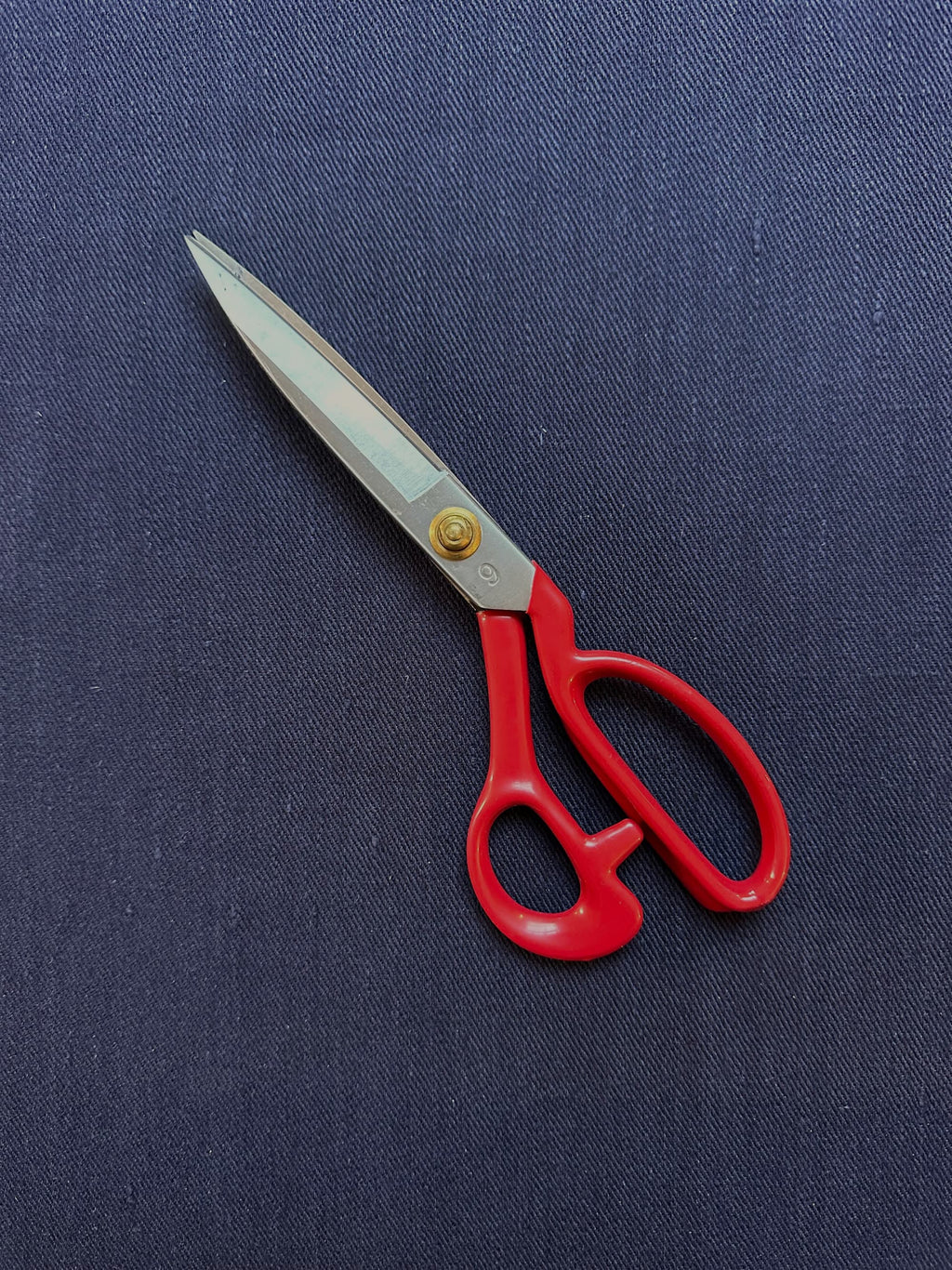 Red-handled scissors on a Cairn indigo blue hemp fabric background