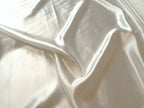 Close-up of cream charmeuse hemp and silk fabric with folds