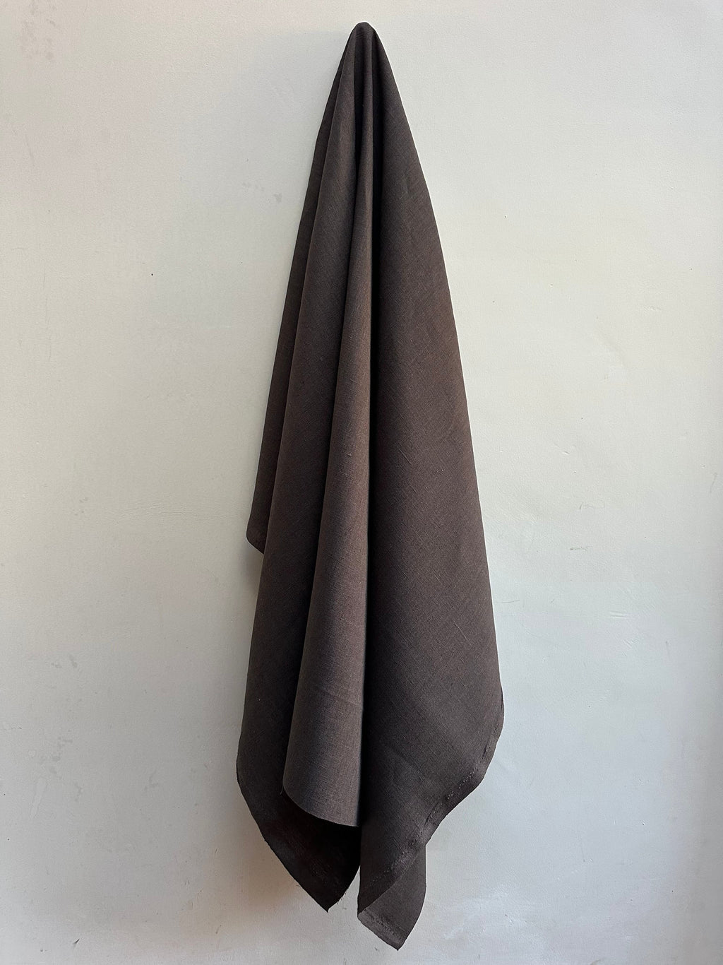 Dama Chocolate Brown hemp fabric hung against a white wall