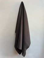 Dama Chocolate Brown hemp fabric hung against a white wall