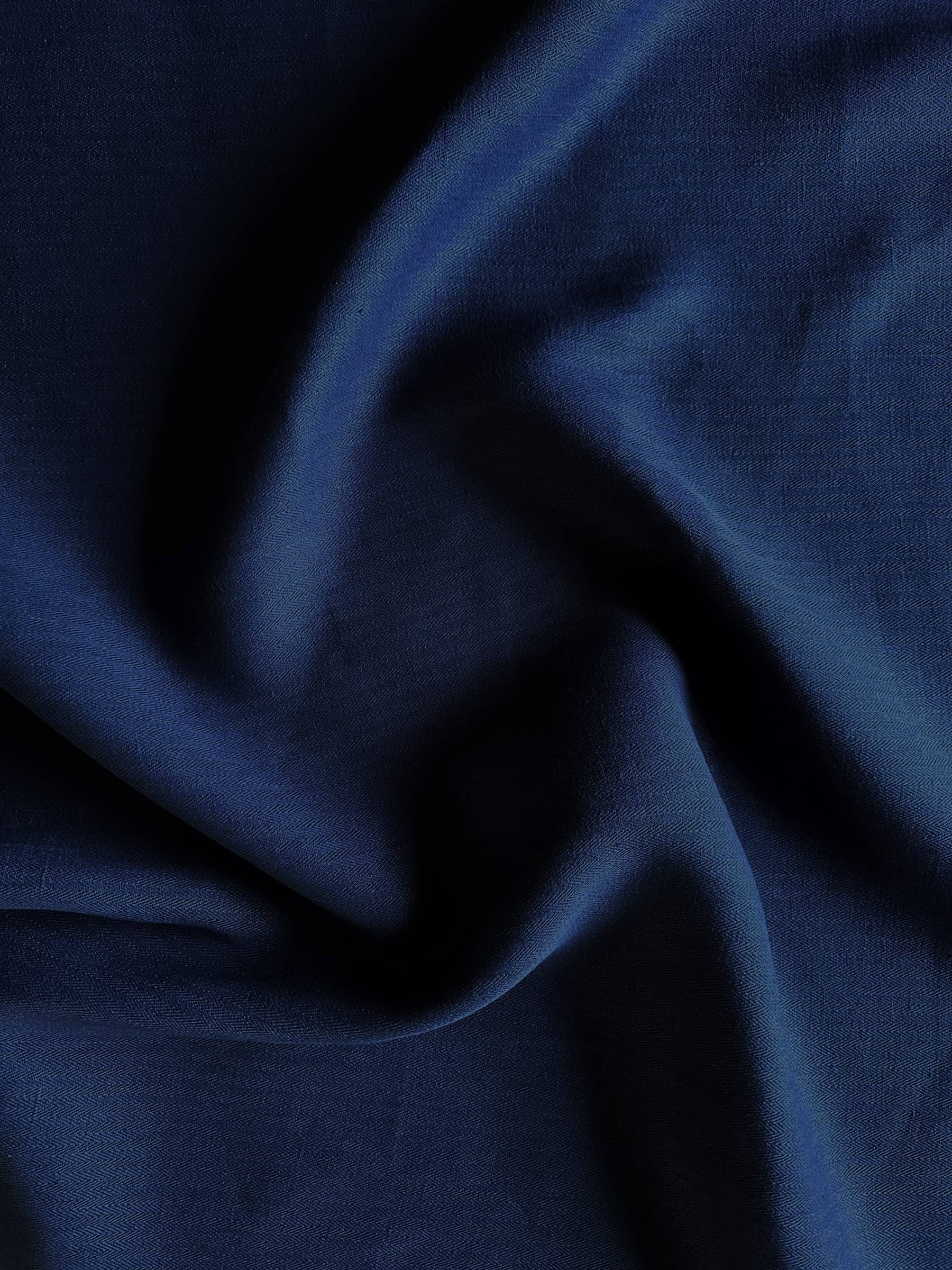 Close-up of dark indigo blue hemp herringbone fabric with folds