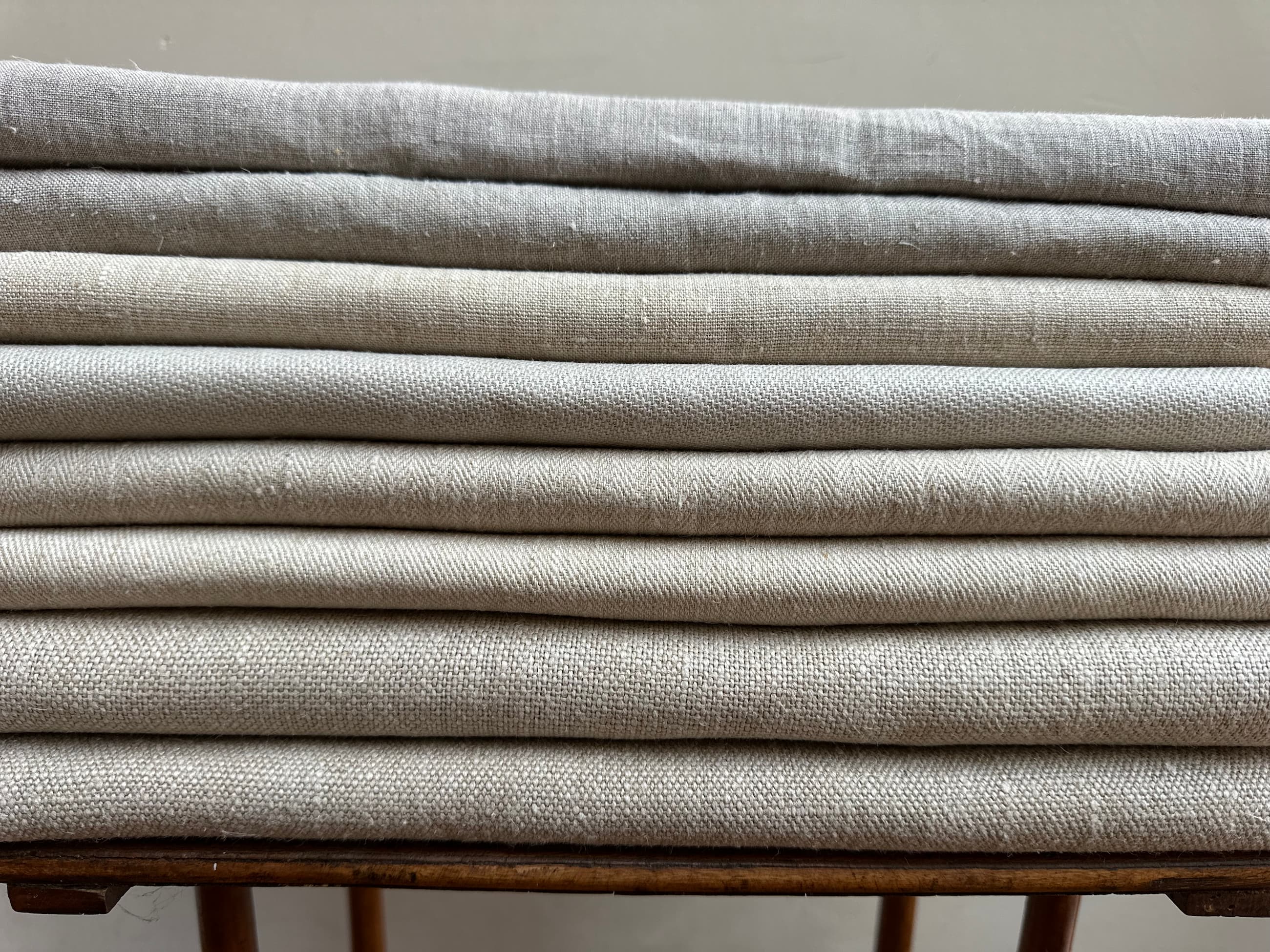 Stack of natural hemp fabric rolls on a wooden surface with a neutral background